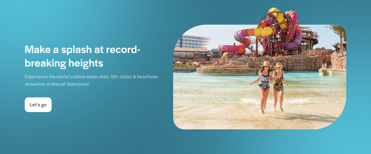Visitors enjoying the beachside at Meryal Waterpark with colorful water slides in the background.